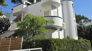 A modern two-story building with a white exterior, a cylindrical structure on the side, and a balcony with a metal railing. - Villa Dyrrahu (Golem)
