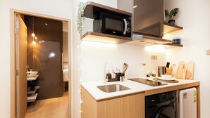 A compact kitchen with a microwave, sink, and dishwasher. - Coliwoo Orchard (Singapore)