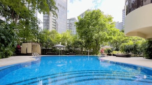 A swimming pool with tiled steps, surrounded by greenery and modern buildings. - Coliwoo Orchard (Singapore)