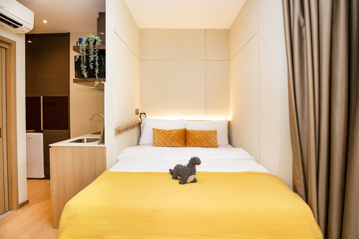 A compact hotel room with a bed, a small kitchenette, and a bathroom.