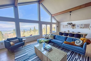Relax in this serene living room with a stunning forest view, featuring a sofa, coffee table, and artwork.