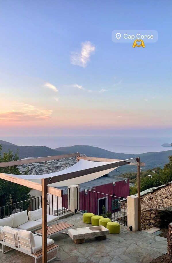 Terraço no telhado com área de estar ao ar livre, vista para o mar e um marcador de localização indicando Cap Corse.