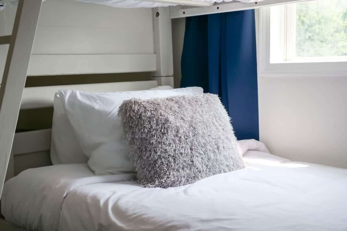 Ein Stockbett mit weißer Bettwäsche und einem flauschigen Kissen.