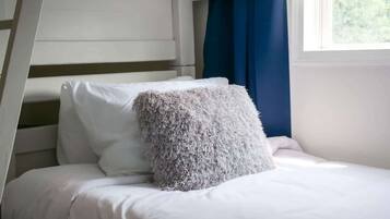Ein Stockbett mit weißer Bettwäsche und einem flauschigen Kissen.