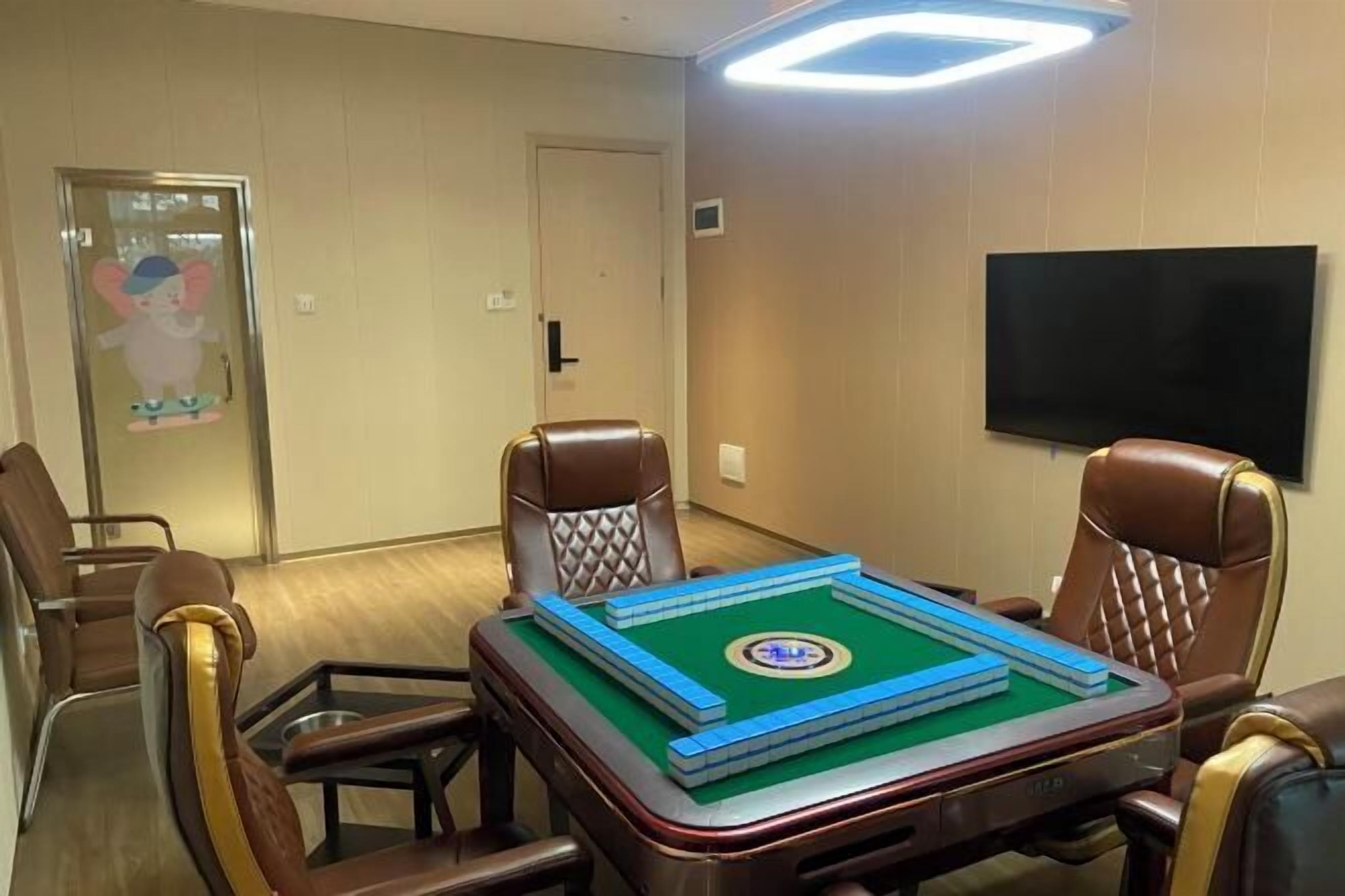 A room with a green snooker table, brown leather chairs, a flat-screen TV, and a door with a cartoon character.