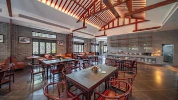 Ein geräumiges Restaurant mit hohen Decken, freiliegenden Balken und verschiedenen Sitzgelegenheiten, darunter Tische und Stühle.