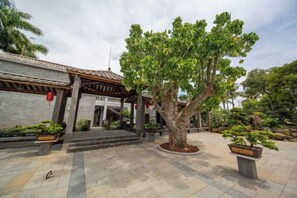 A traditional building with a tiled entrance, a central tree, and potted plants. - Longquan Xiangyuan Shared Farm (Wenchang)