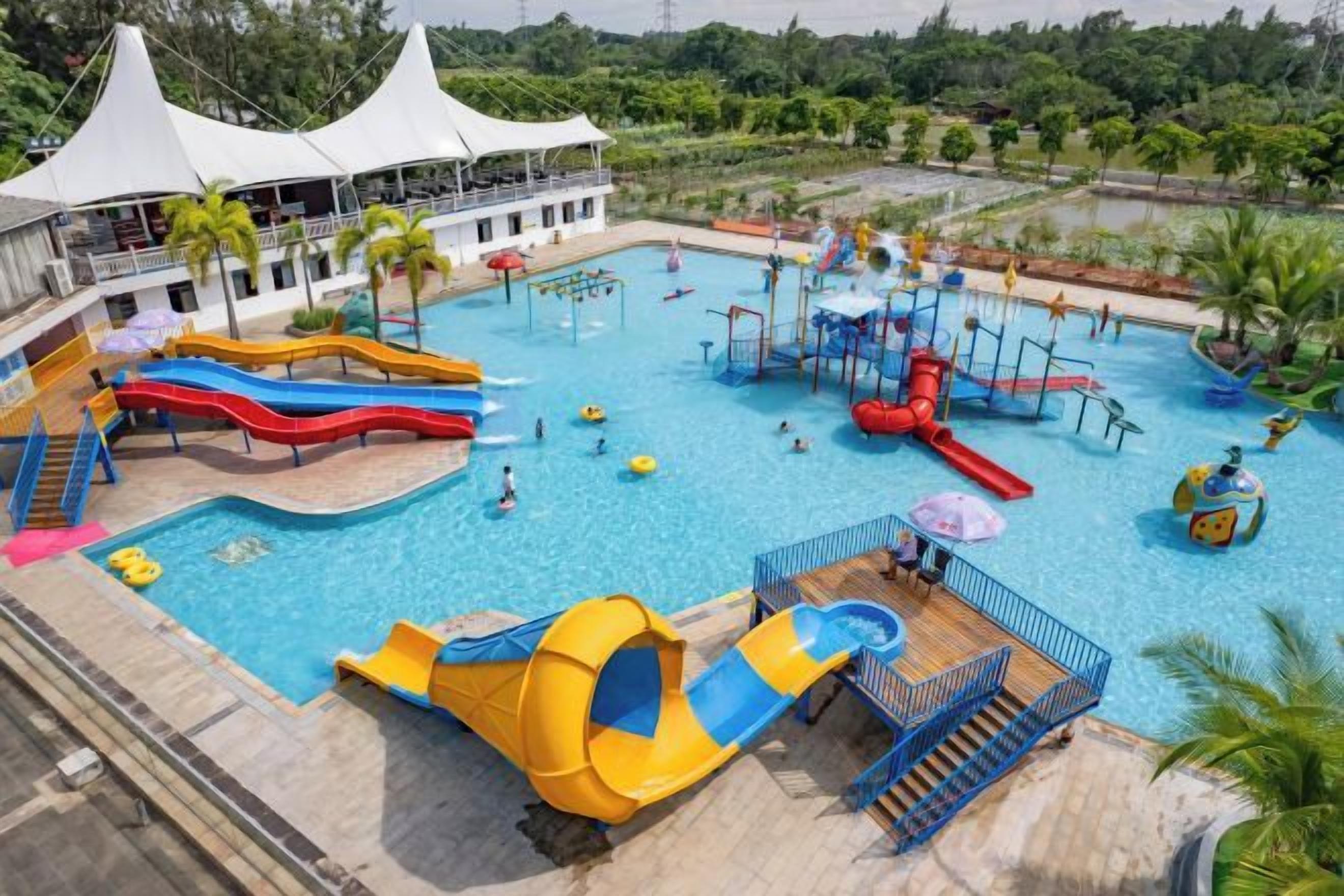Een waterpark met verschillende glijbanen en zwembaden, omgeven door een gebouw met witte zonnedaken.