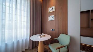 A modern room with a round table, a light green chair, wooden panel walls, and two framed pictures.