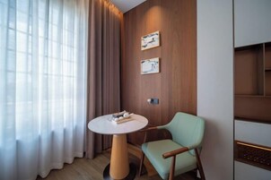 Una habitación moderna con una mesa redonda, una silla verde clara, paneles de madera y dos cuadros enmarcados.