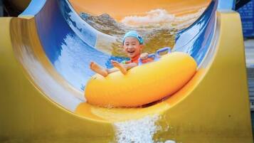 A child on a yellow water slide with a wave background.