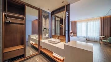 A modern hotel room with a large mirror, a wooden vanity, a bed, and a desk.