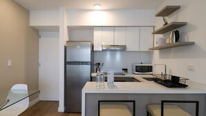 A modern kitchen with a refrigerator, microwave, and a small island with stools.