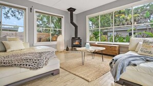 Ein gemütliches Wohnzimmer mit Kamin, großen Fenstern und einer bequemen Sitzecke.