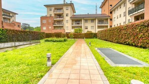 Un camino que lleva a un edificio residencial con varios balcones y un jardín bien cuidado.