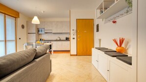 Una cocina moderna con armarios blancos, una puerta de madera y un comedor con sofá y mesa.