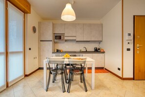 A modern kitchen with a dining table, chairs, a microwave, and a hanging light fixture.