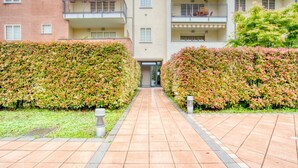 Un sendero que conduce a un edificio con varios balcones y setos a ambos lados.