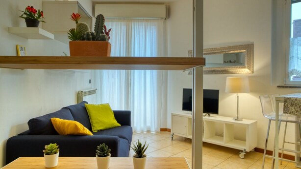 A modern living room with a sofa, a coffee table, a TV, a lamp, and a small dining area. - CaseOspitali - CASA CERTOSA pochi min da Rho Fiera (Milan)
