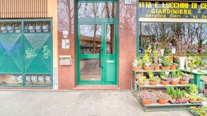 A storefront with a green door, a signboard, and potted plants outside. - CaseOspitali - CASA CERTOSA pochi min da Rho Fiera (Milan)