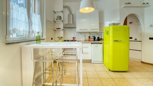 A kitchen with white cabinets, a bright yellow refrigerator, a hanging light fixture, and a window with curtains. - CaseOspitali - CASA CERTOSA pochi min da Rho Fiera (Milan)