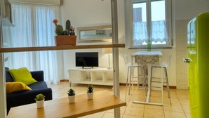 A modern living room with a sofa, TV, dining table, and potted plants. - CaseOspitali - CASA CERTOSA pochi min da Rho Fiera (Milan)