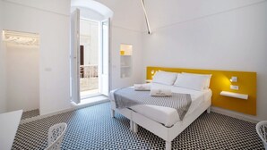 Una habitación de hotel moderna con cama, una mesita, una silla y un balcón.