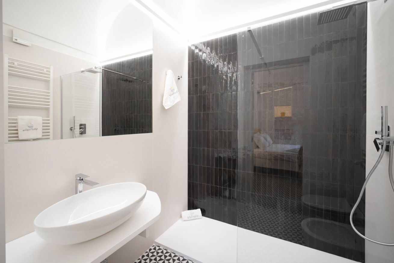 A modern bathroom with a white sink, a glass shower enclosure, and a visible towel rack.