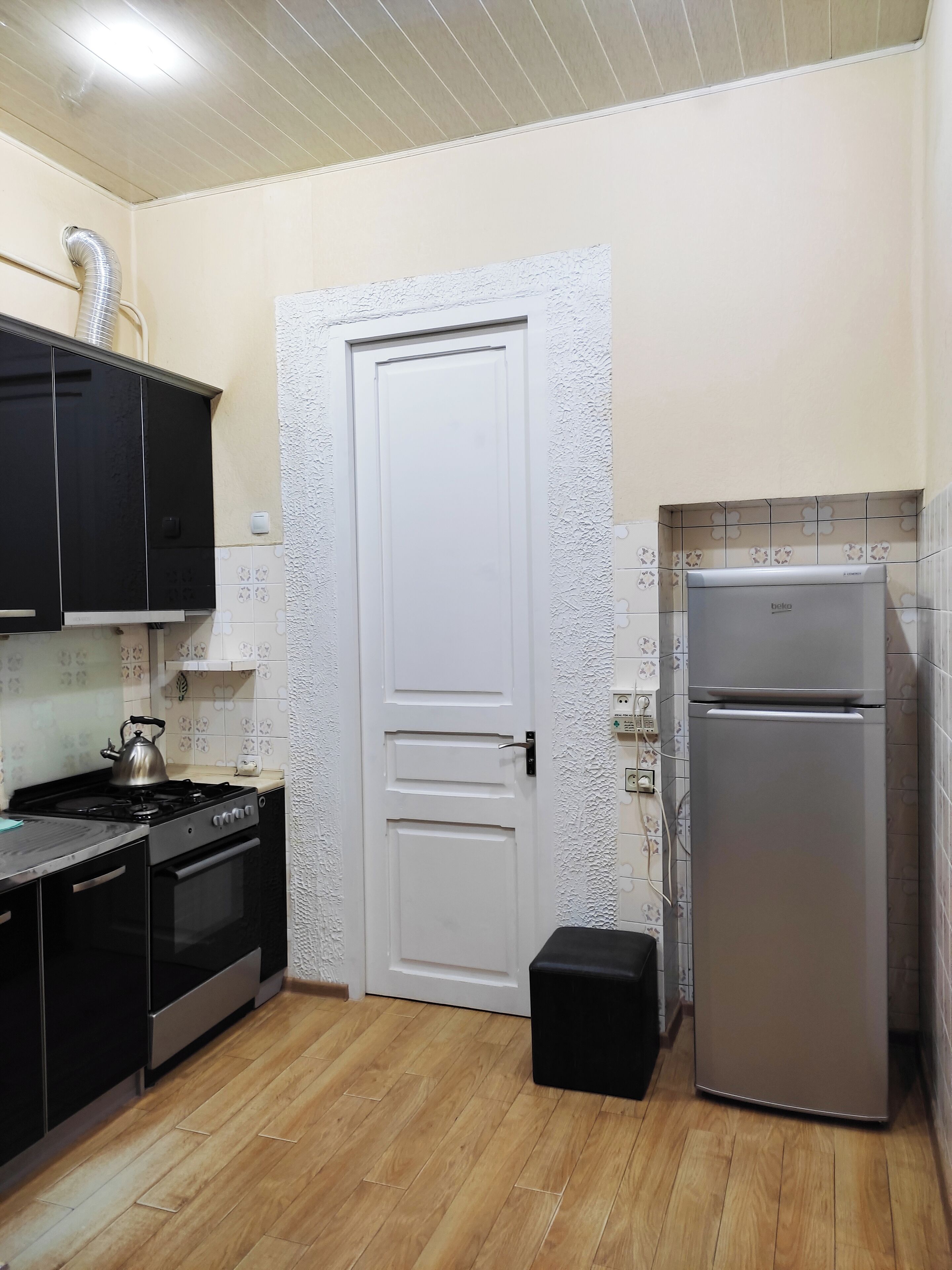 A kitchen with a stove, oven, refrigerator, and black cabinets.