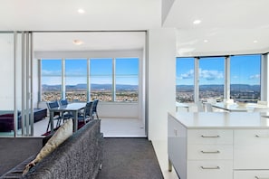 A modern interior with a dining area, a sofa, and a kitchen with a view of a cityscape.