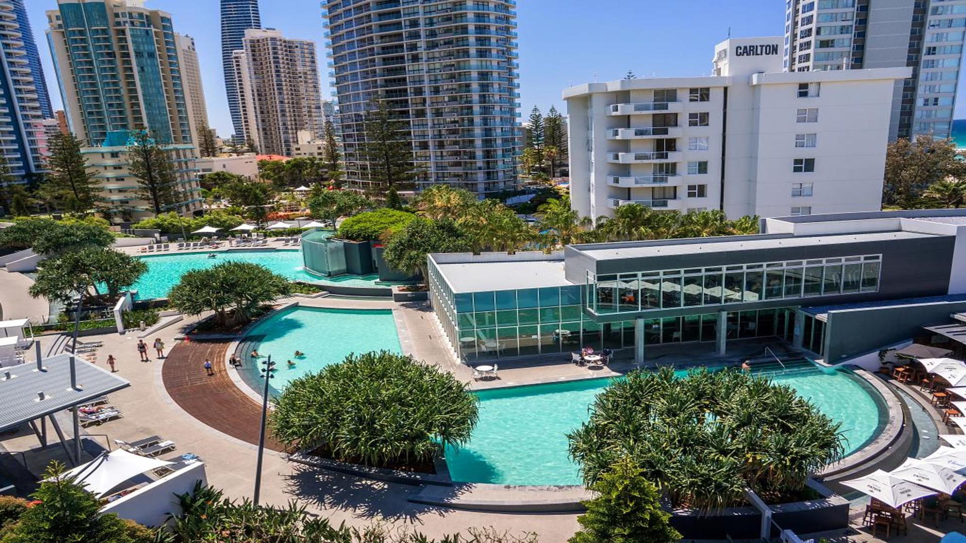 Un hôtel moderne doté de plusieurs piscines, entouré d’immeubles de grande hauteur.