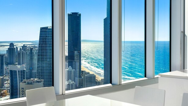 A modern hotel room with large windows offering a view of a city skyline and the ocean. - Stunning 2 Bedroom Ocean Views Apartment - CoastHM (Surfers Paradise)