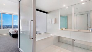 A modern bathroom with a large mirror, a bathtub, and a shower area.