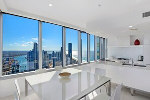 A modern kitchen with a large window overlooking a cityscape and the ocean. - Stunning 2 Bedroom Ocean Views Apartment (Surfers Paradise)