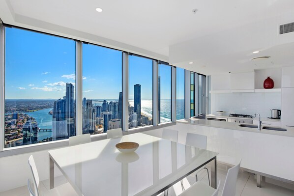 A modern kitchen with a large window overlooking a cityscape and the ocean.