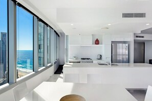 A modern kitchen with a large island, a view of the ocean, and a cityscape. - Stunning 2 Bedroom Ocean Views Apartment (Surfers Paradise)