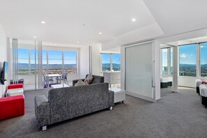 A modern hotel room with a city view, a sofa, a dining area, and a bed. - Stunning 2 Bedroom Ocean Views Apartment (Surfers Paradise)