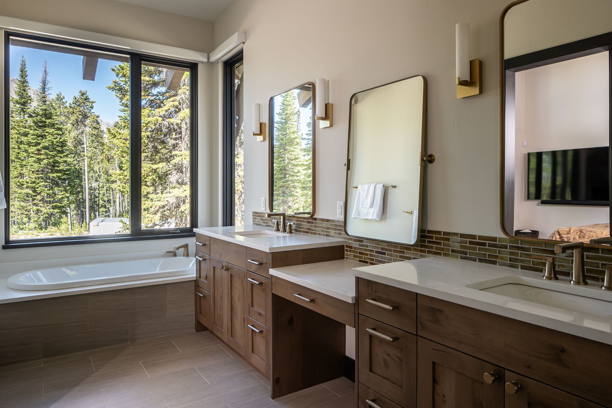 A modern bathroom with two sinks, wooden cabinets, and large mirrors.