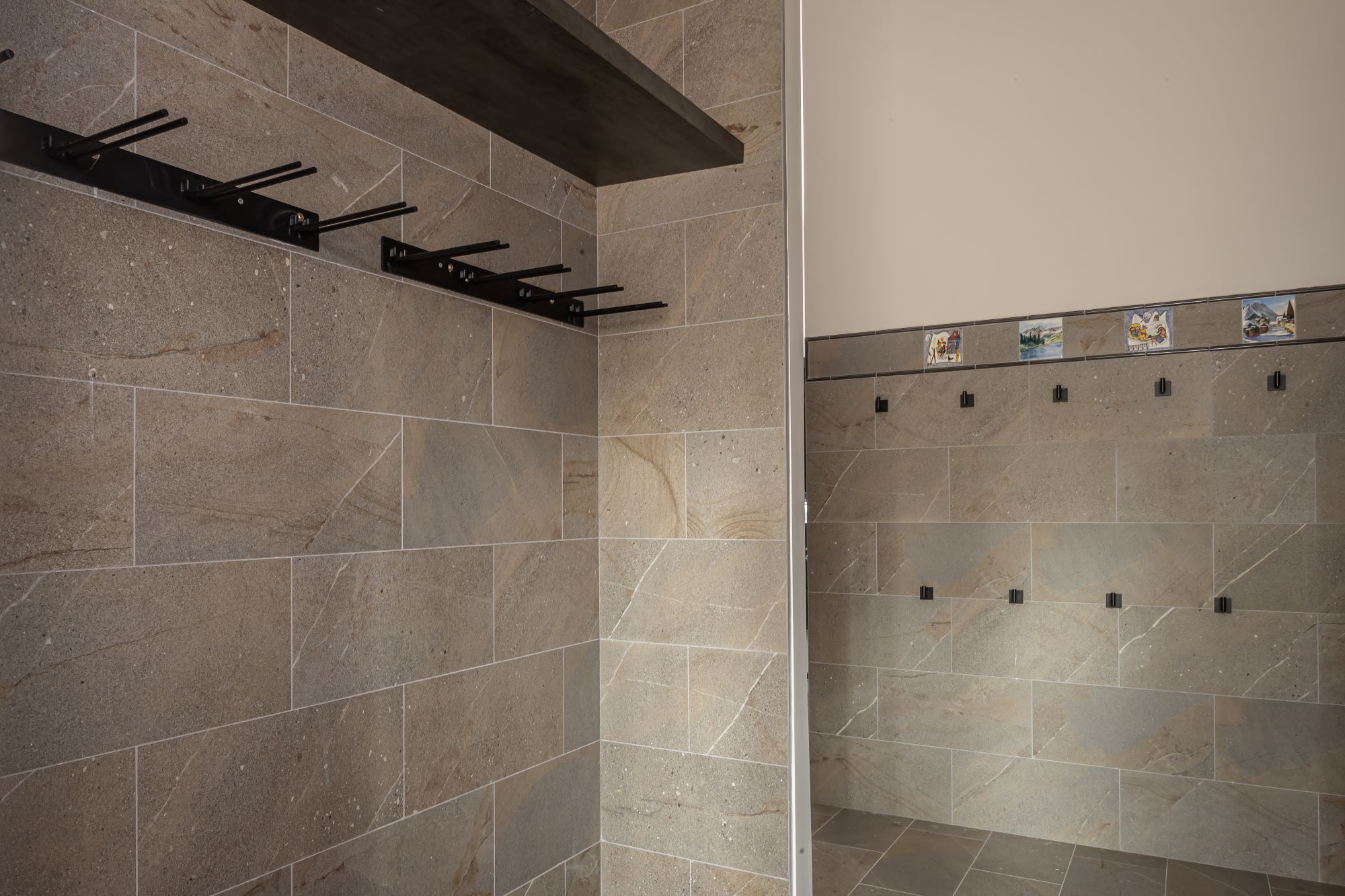 Un baño con baldosas color beige, un perchero de metal y una pared de azulejos con detalles decorativos.