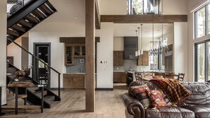 Un vaste espace de vie comprenant un canapé en cuir, un escalier et une cuisine avec des meubles en bois.
