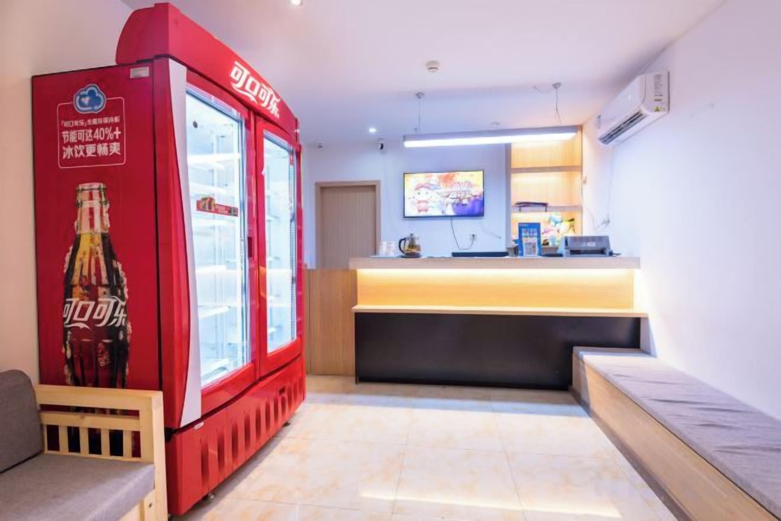 A hotel lobby with a reception desk, a red beverage dispenser, and a television screen.