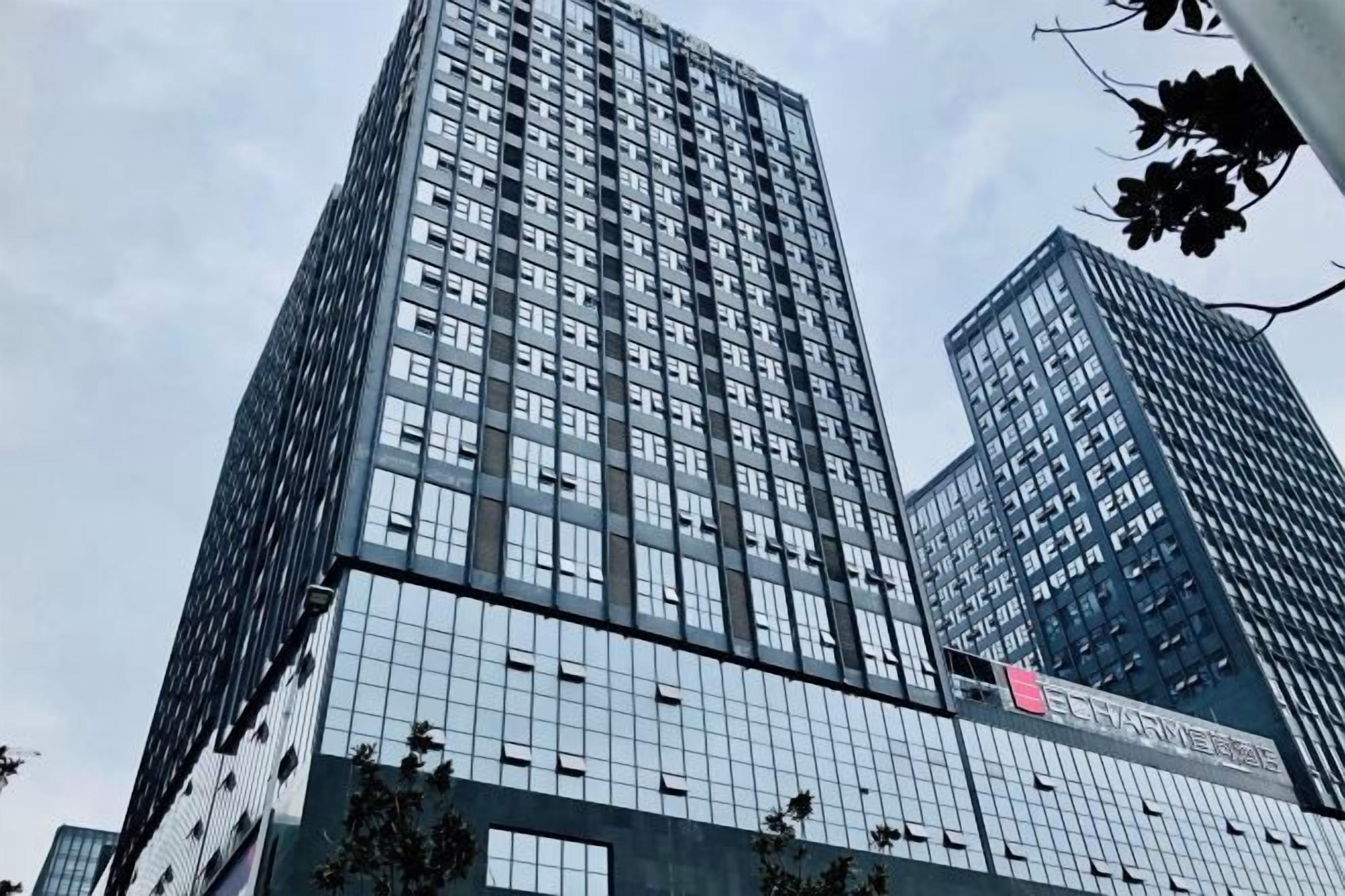 A tall, modern building with a glass facade and a prominent logo on the side.