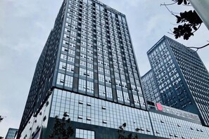 Un edificio alto y moderno con fachada de vidrio y un logotipo destacado en un lateral.