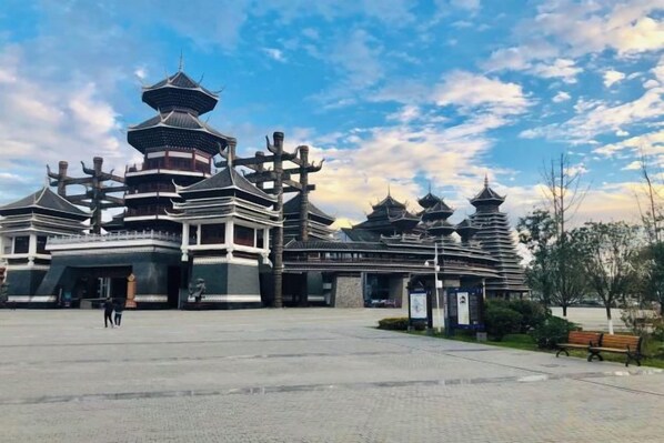 Un edificio tradicional de estilo pagoda con varios niveles, un patio empedrado y cielo despejado.