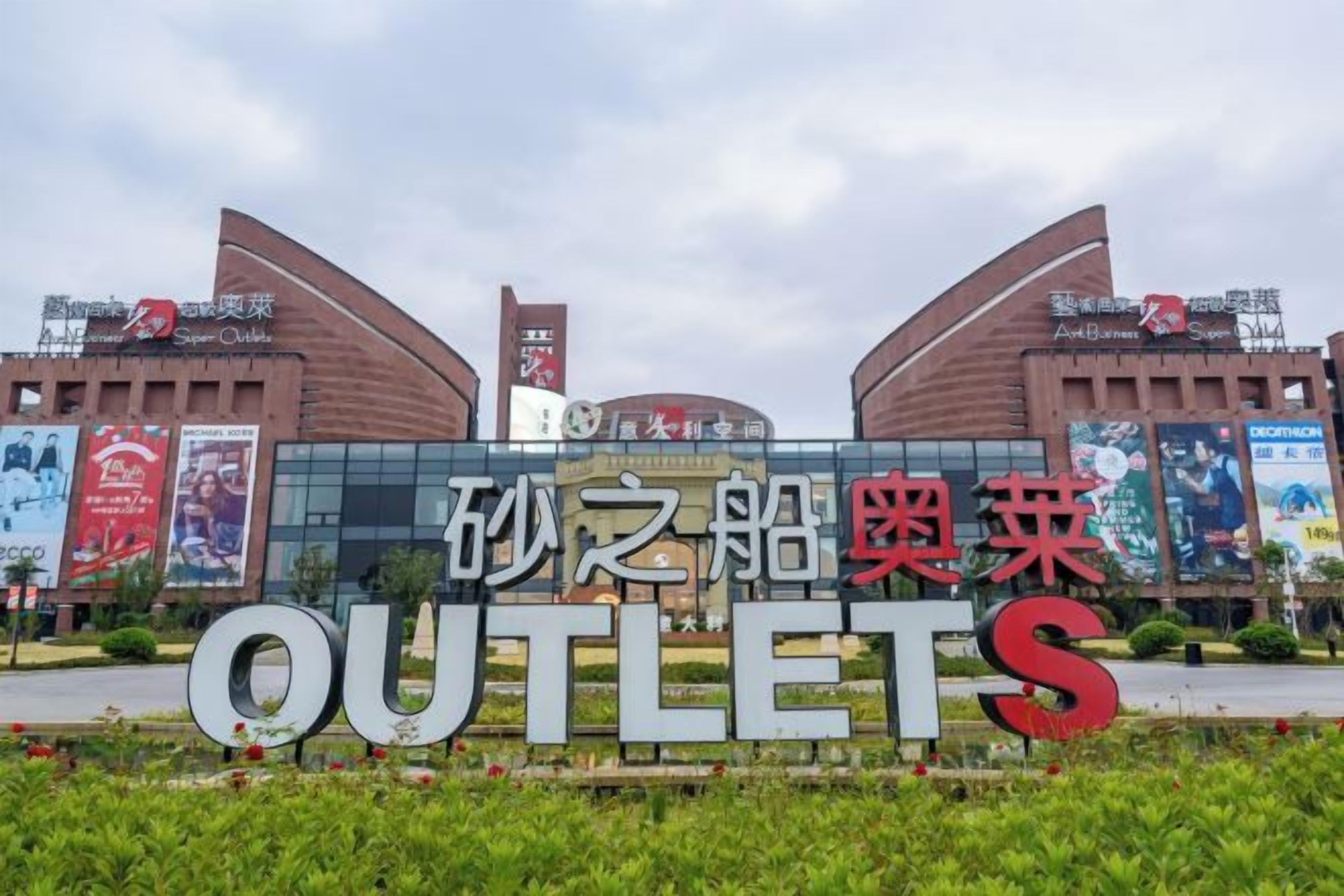 A sign for a shopping center with the name 'OUTLETS' and Chinese characters.