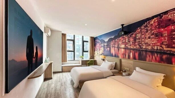 A hotel room with two beds, a large window, and a cityscape mural on the wall. - 24 Hours Banxing Hotel (Guiyang)