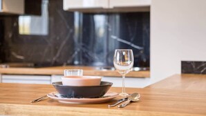 Eine moderne Küche mit Marmorfliesenspiegel, einem Holztisch, einer Schüssel, einem Glas und einem Weinglas.