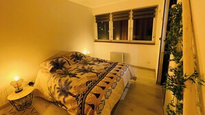 Ett sovrum med en säng, sänglampor, ett element och ett fönster med persienner.