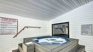 Un jacuzzi con cubierta de madera y baranda de madera. Hay carteles en las paredes con normas de uso del jacuzzi.