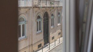 Un edificio con detalles arquitectónicos ornamentales, incluyendo un balcón con barandillas intrincadas y una entrada arqueada grande.